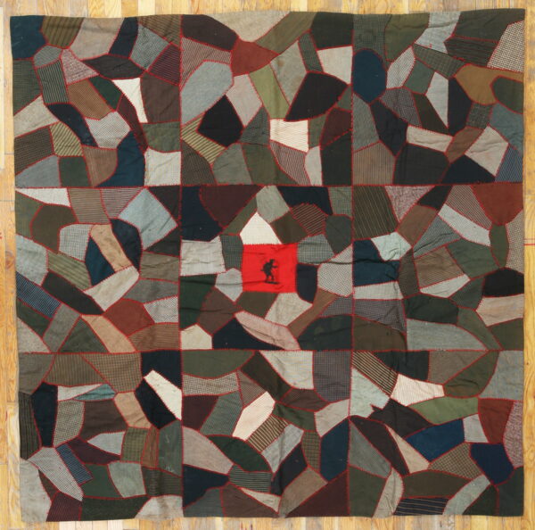 Flat textile rug with irregular dark patches and red stitching; a central red square features a black silhouette.