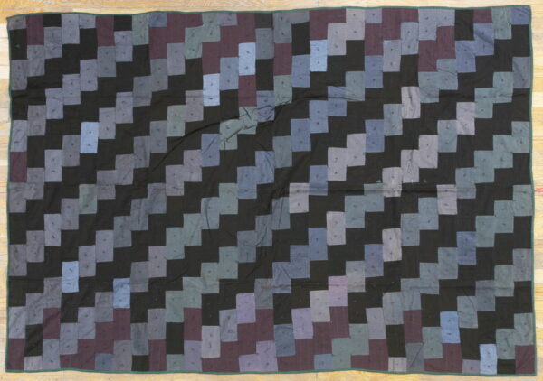 Flat textile featuring a staggered diagonal pattern in black and shades of dusty blue, gray, and mauve.