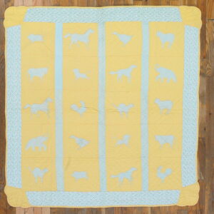 Yellow and blue quilted rug featuring various light blue animal silhouettes and a geometric border on wood planks.