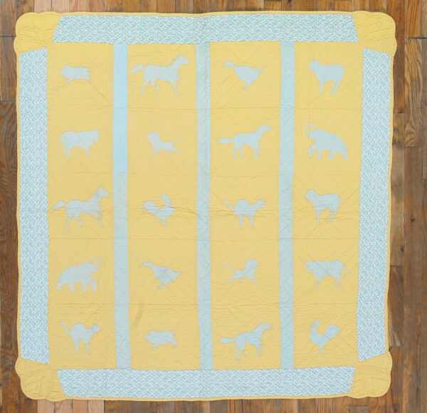 Yellow and blue quilted rug featuring various light blue animal silhouettes and a geometric border on wood planks.