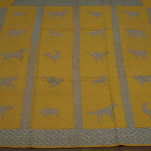 Quilted yellow rug featuring gray animal silhouettes and a patterned blue-green trim on dark wood flooring.
