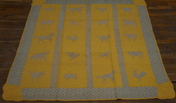 Quilted yellow rug featuring gray animal silhouettes and a patterned blue-green trim on dark wood flooring.