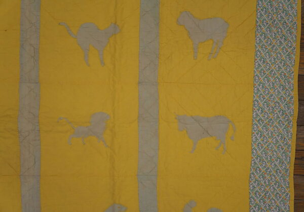 Yellow rug pattern featuring gray animal silhouettes, vertical gray columns, and a mint green patterned border.