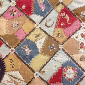 A low-pile textile featuring multicolored patchwork diamonds stitched together with detailed embroidery.