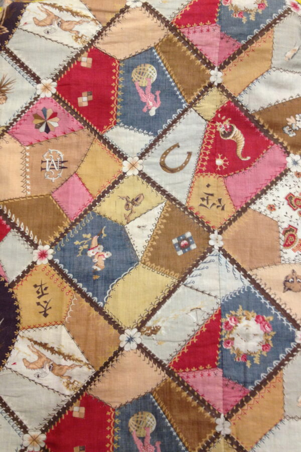 A low-pile textile featuring multicolored patchwork diamonds stitched together with detailed embroidery.