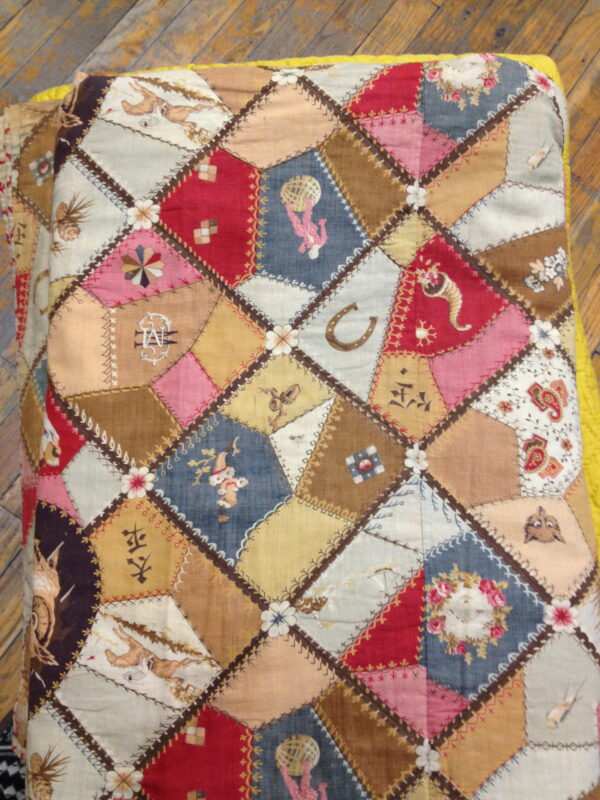 Low-pile textile with a complex diamond patchwork pattern in reds, blues, browns, and illustrative motifs on a wood floor.