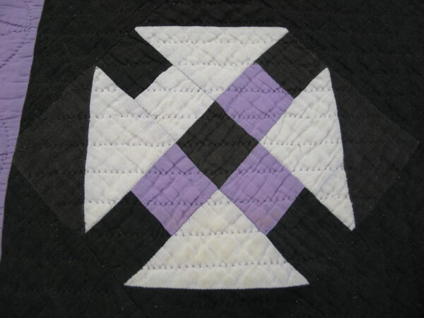 Geometric quilted pattern in black, white, and lavender fabric showing stitched diamond texture.