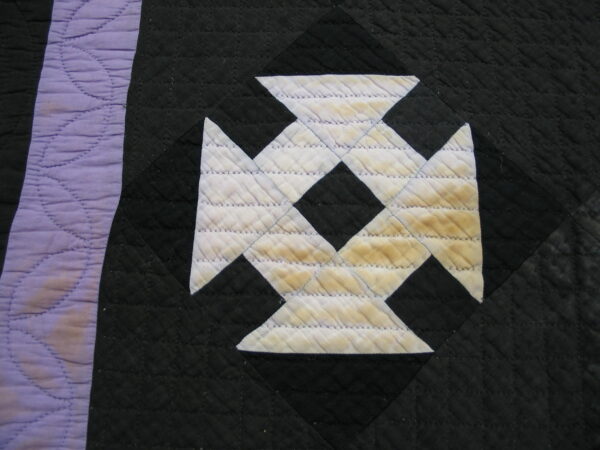 Quilted black textile with a pale lavender stripe and a distressed white geometric pattern showing stains.