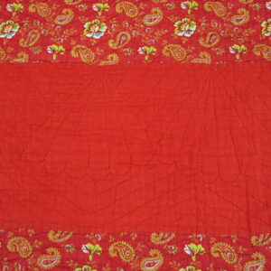 Red quilted textile featuring a stitched fan design bordered by yellow and green paisley motifs.