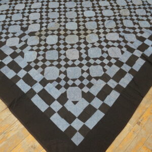 Low pile black and light blue geometric textile covers distressed diagonal wooden floorboards.