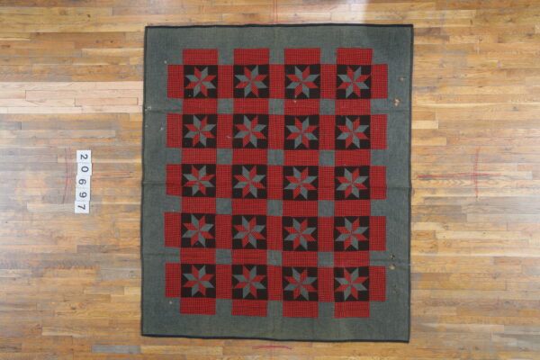 Red and black star quilt block motifs alternate with red checkered squares on a dark gray rug.