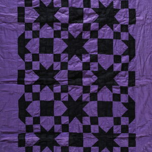 Wrinkled flat textile with a bold, geometric star and checkerboard pattern in purple and black.