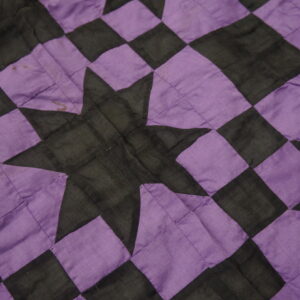 Detail of a low-pile textile featuring a purple and black checkered pattern and a central star design.