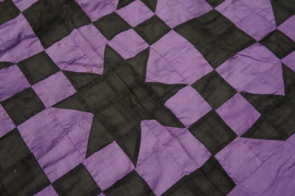 Detail of a low-pile textile featuring a purple and black checkered pattern and a central star design.