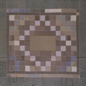 Patchwork rug featuring a taupe center surrounded by a border of checkered neutral and blue squares.
