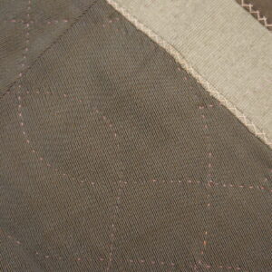 Dark ribbed patches with faint pink dotted patterns are joined by criss-cross stitching to light beige fabric.