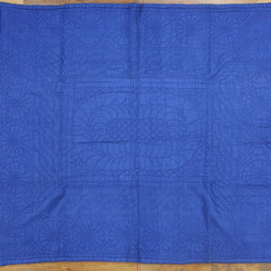 Bright blue stitched area rug with repeating circular geometric patterns resting on a wood floor.