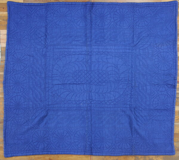 Bright blue stitched area rug with repeating circular geometric patterns resting on a wood floor.