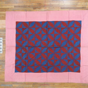 A flat textile featuring a central geometric pattern of red and blue petal shapes with a wide pink border.