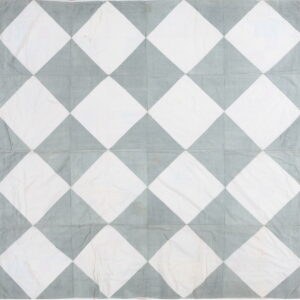 Flat textile with large harlequin pattern in white and muted blue-gray fabric panels.