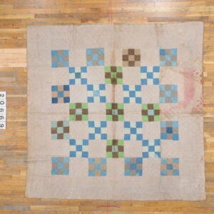 Low-pile beige textile with a geometric blue, green, and brown patchwork design rests on hardwood flooring.