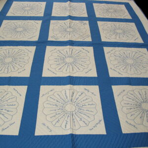White squares featuring blue hand-drawn floral patterns and signatures are set within a grid of quilted blue fabric.
