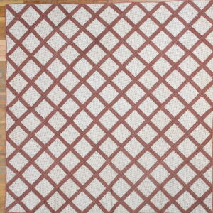 Cream rug with a reddish-brown lattice pattern and small interior dots on a light wood plank floor.