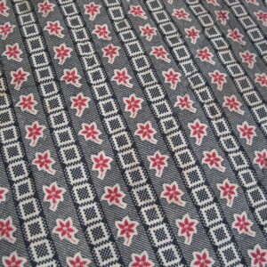 Dark blue rug with white geometric stripes and rows of stylized pink and white five-petal flowers.
