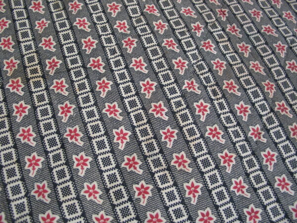 Dark blue rug with white geometric stripes and rows of stylized pink and white five-petal flowers.