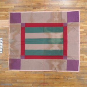 Square textile with red, teal, and mauve striped center, purple corners, and low-contrast patterned borders on a wood floor.