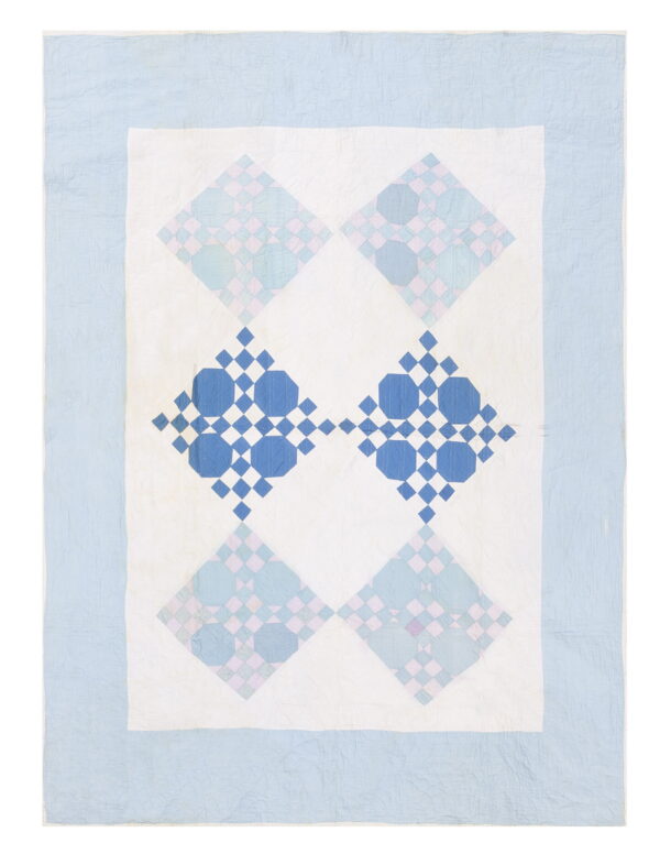 Flat woven textile in blues and white featuring four large geometric diamond patterns surrounded by a light blue border.