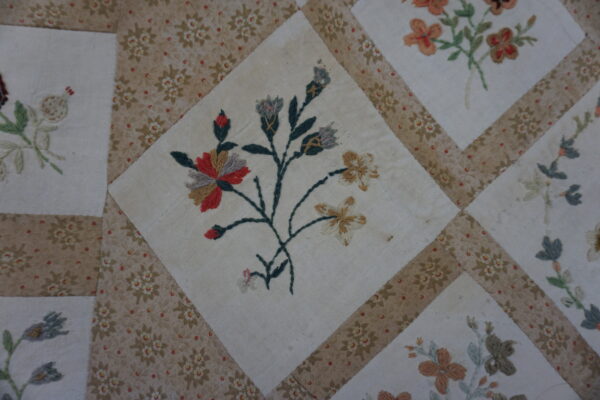 Close view of a high-pile needlework textile featuring multicolored floral diamonds bordered by printed beige strips.