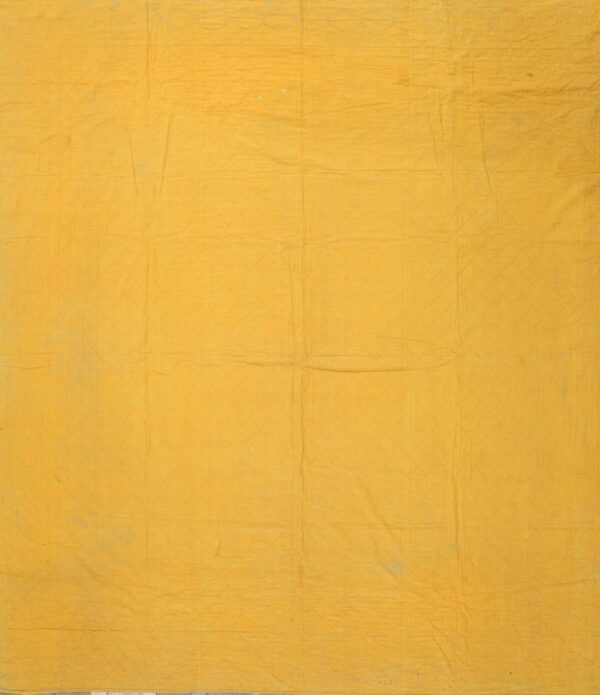 Solid yellow fabric backing displaying faint quilted stitch lines in a diamond pattern across the surface.