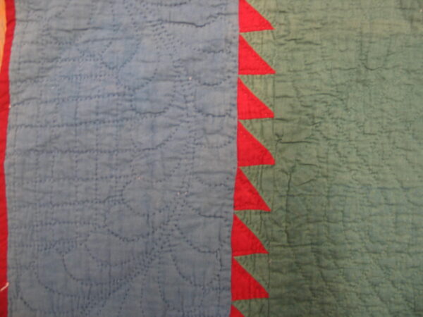Stitched blue and muted green fabric with a bright red vertical border of sawtooth triangles.