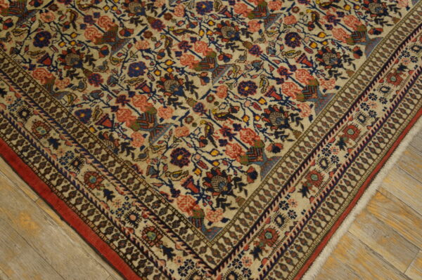 Antique qum iran knotted rug 7 Cream rug featuring red and blue stylized floral patterns and a detailed border on distressed wooden planks.