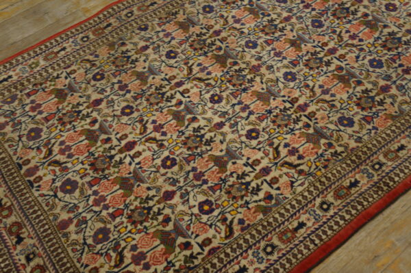 Antique qum iran knotted rug 6 Dense floral and avian motifs in blue, red, and brown cover the cream rug on light wood planks.