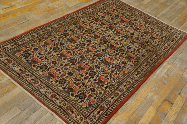 Antique qum iran knotted rug 3 Multicolored low-pile rug with dense floral and bird design and red trim on distressed wood flooring.