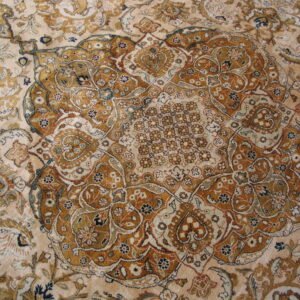 Low-pile rug displays a detailed medallion and dense traditional pattern in cream, gold, rust, and navy.