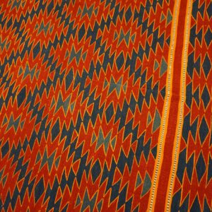 Red-orange and dark blue flatweave rug with densely packed jagged geometric patterns and a distinct striped border.