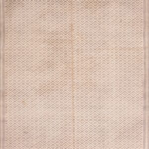 Geometric high-pile rug in beige and navy blue with a striped border beside distressed wood flooring.