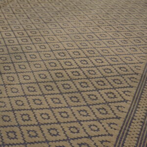 High-low pile rug in beige and dark blue features a repeating geometric diamond pattern on wood floor.