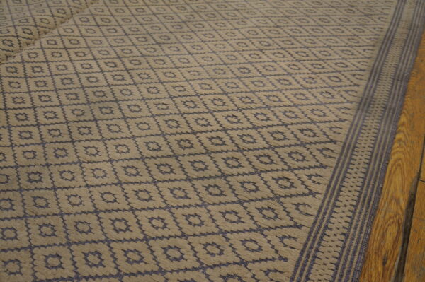 High-low pile rug in beige and dark blue features a repeating geometric diamond pattern on wood floor.