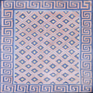 Blue and blush pink geometric rug featuring a Greek Key border and repeating central diamond patterns.