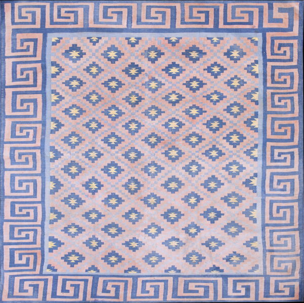 Blue and blush pink geometric rug featuring a greek key border and repeating central diamond patterns.
