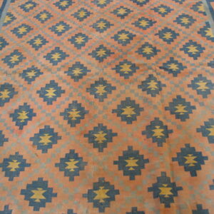 Geometric rug with large navy and yellow motifs on a peach and pale blue checkered field and key border.