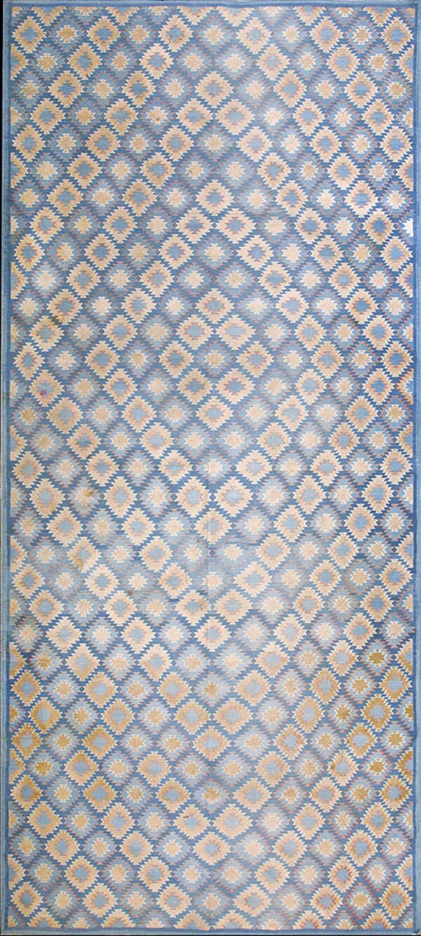 Rectangular rug with a blue field filled with repeating jagged diamonds in tan and light blue.