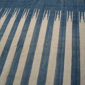 Textured blue and cream flatweave rug with vertical stripes featuring jagged geometric terminations at the top edge.