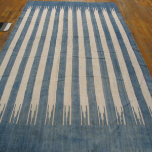Low-pile rug with wide blue and cream vertical stripes, featuring stylized jagged ends on wood floor.