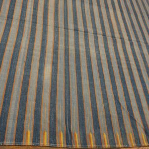 Blue and gray-blue striped rug with orange accent lines resting on a dark wood floor.