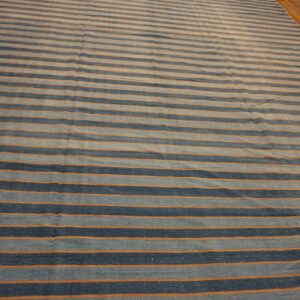 Striped blue and orange low-pile rug lying on a glossy light brown hardwood floor.